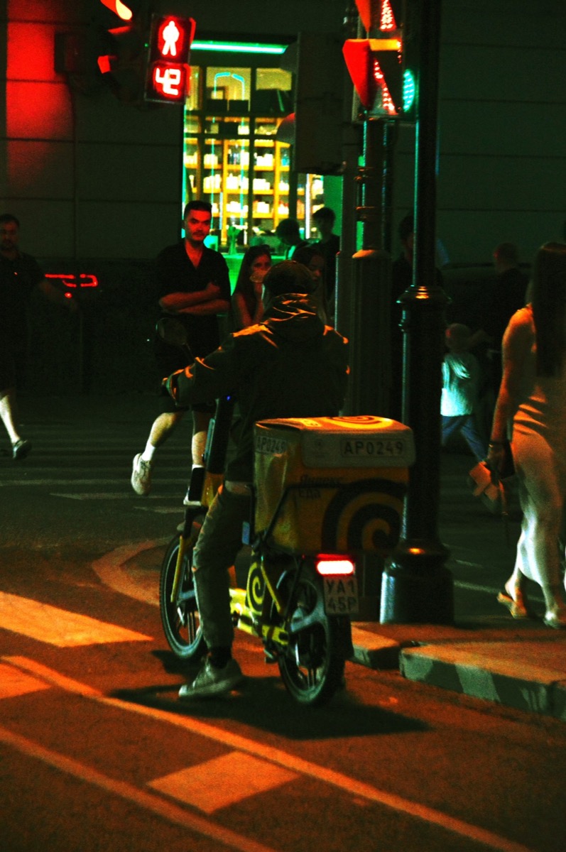 A delivery rider at a city intersection at night
